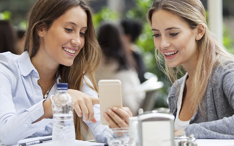 Two people at meeting. One is showing the other someone on her phone