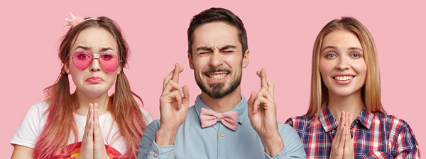 diverse group of people with fingers crosses or hands in prayer position