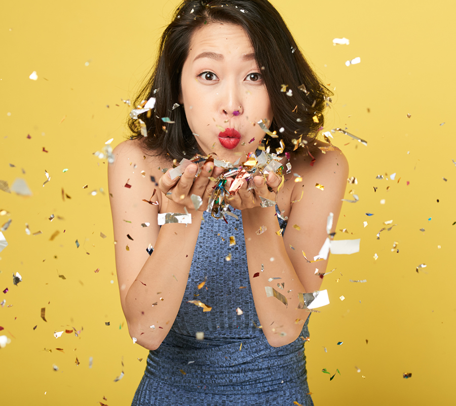 Young Asian woman blowing confetti